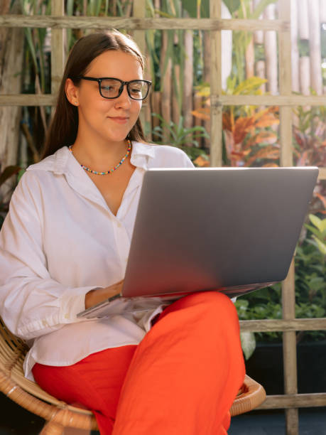istock Confident young woman working on laptop while sitting near window in creative office or cafe 1459850179