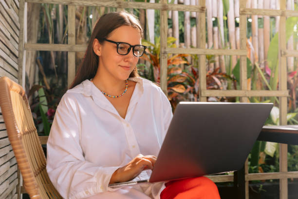 istock Woman freelancer working on laptop while sitting near window in creative office or summer cafe 1459850220