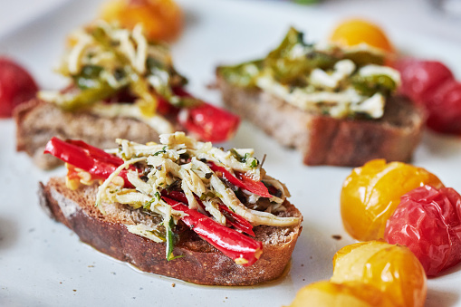 Delicious open faced sandwich, topped with cherry tomatoes, chili pepper and shredded chicken meat