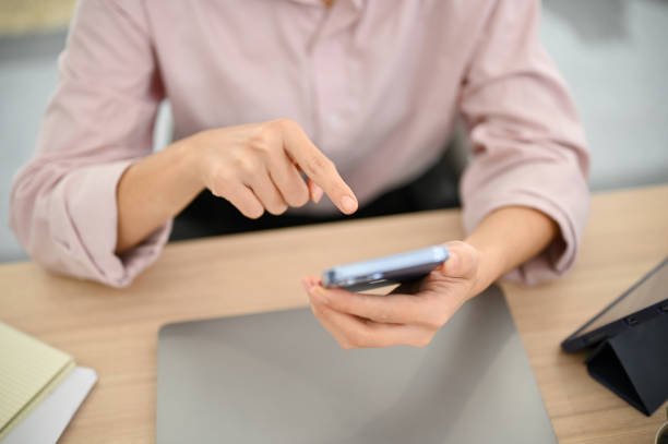 istock Top view of a female office worker using a smartphone at her desk, using mobile application 1459852880