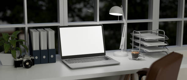 istock Modern urban office desk with laptop mockup, table lamp, binder, document tray on table 1459853418
