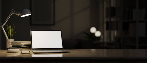 istock Workspace tabletop with laptop mockup, light from table lamp over blurred darkness room 1459853420