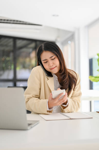 istock Busy Asian businesswoman using calculator while dealing business with her client over the call. 1459858598