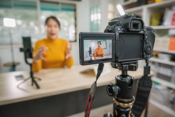 istock Asian woman vlogger live streaming from her office using camera tutorial video to social network by internet at home 1459869868