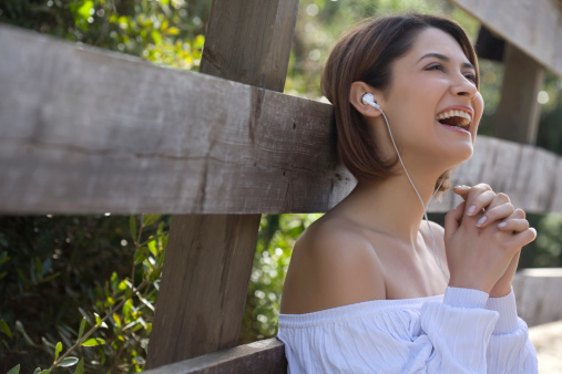 young girl laughing and listening to music outodoor