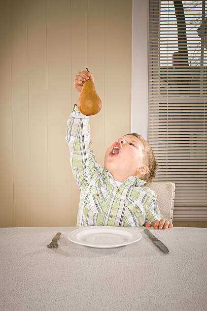 Boy holding pear and about to eat it stock photo