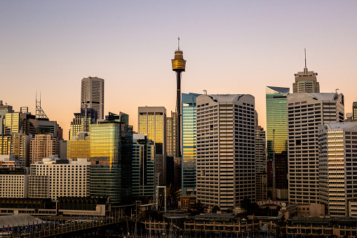 A distance photo of Sydney's CBD at the start of sunset with reflections on all the glass windows