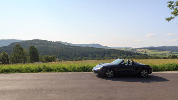 roadster azul porsche boxster 986 con panorama de wasserkuppe en las montañas de rhön. - germany landscape nissan roadster fotografías e imágenes de stock