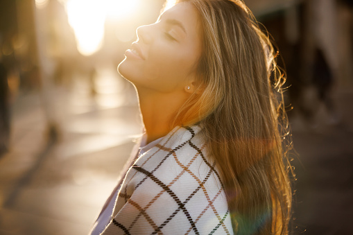 Close-up shot of beautiful young woman at sunset in the city