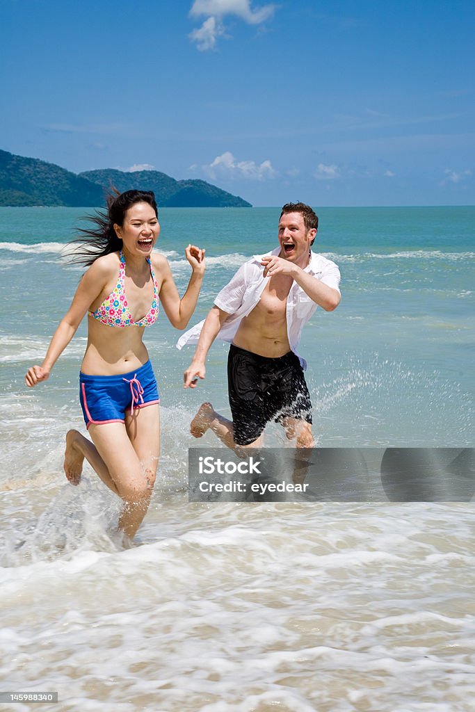 Casal correndo tempos freneticamente na praia com alegria - Foto de stock de Correr royalty-free