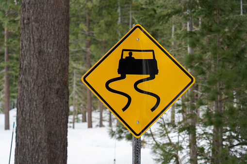 Slippery road sign with snowy forest backdrop