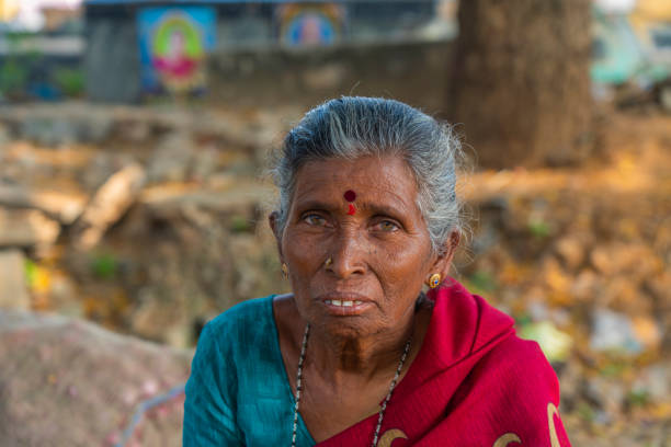 Indian old lady with gray hair, close up, looking in the camera at a vegetable market in Puttaparthi stock photo