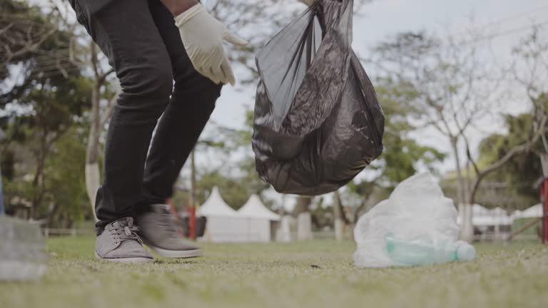 Young man collecting trash in a park during a community clean-up project