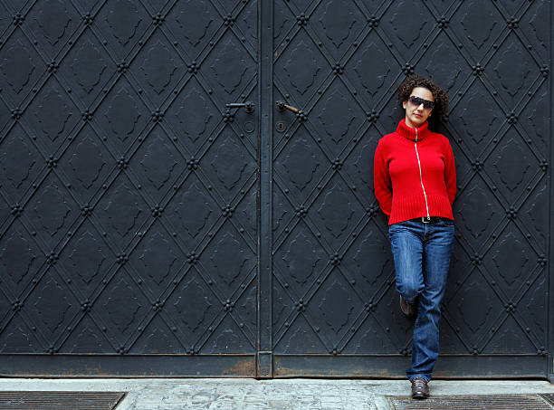 woman stands against a gate stock photo