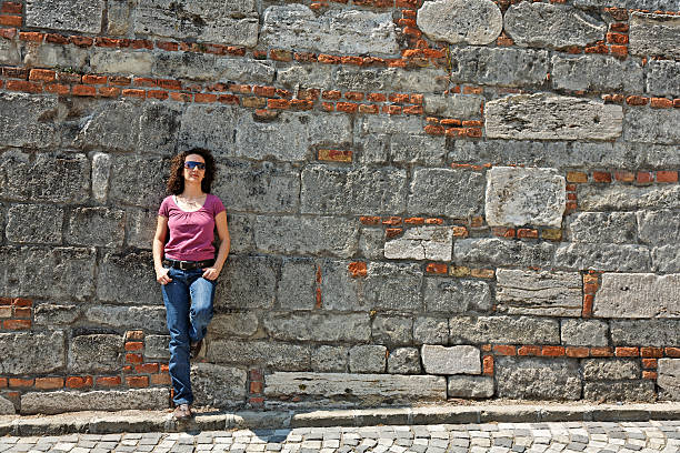 woman stands against a stone wall stock photo