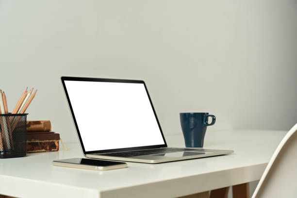 istock Laptop computer with blank screen, tablet, books and cup of coffee on white table. 1459892251
