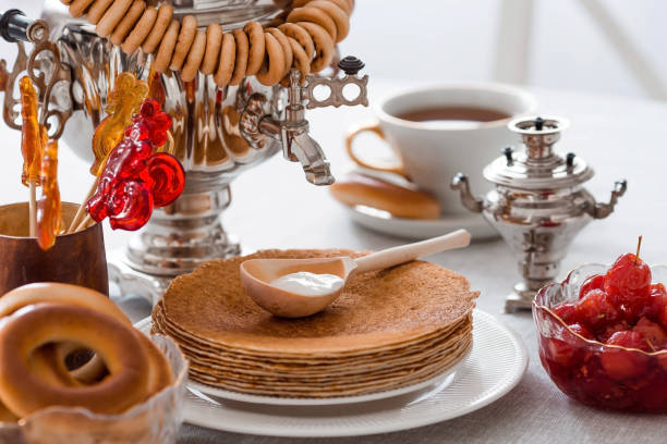 russian traditions. russian holiday maslenitsa. still life with a cup of tea, a stack of pancakes, sour cream, honey, cubes of butter, bagels, dried fruits, caramel cockerel and samovars. - costume stage costume sunlight carnival imagens e fotografias de stock