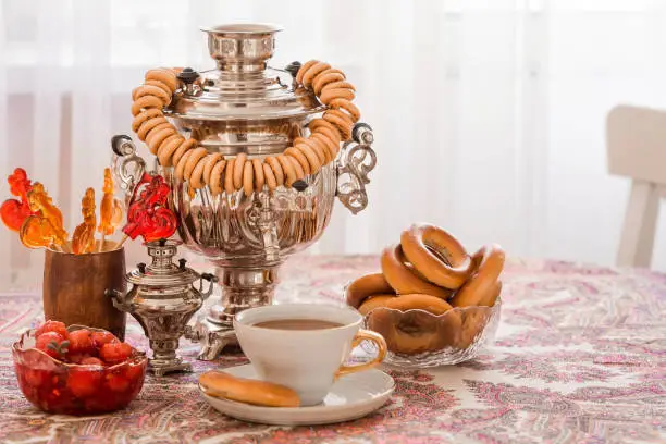 Russian traditions. Tea drinking with a samovar. Still life with a cup of tea, bagels, dried fruits, apple jam, caramel cockerel and Russian samovars.
