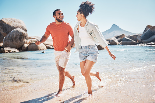 Black couple, beach and running while happy on vacation in summer with energy, love and happiness while outdoor. Man and woman together by the sea for honeymoon, holiday and quality time in nature