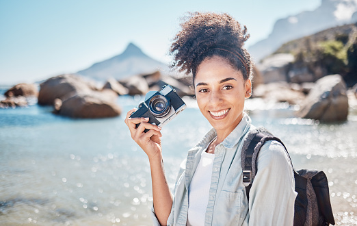 Black woman, beach photographer and camera on ocean travel holiday, adventure by the sea and summer vacation. Portrait of freelance photography professional, tourist by the seaside and girl in nature