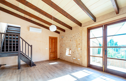 Open plan empty master bedroom with parquet floors, wooden beams, balcony and air conditioning in rustic style