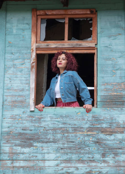 Young red-haired beautiful girl laughing through a broken window