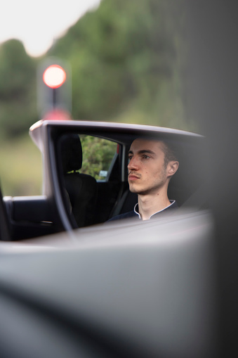 A young blonde driver standing at a red light