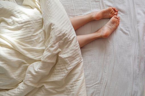 A woman's legs stick out from under her blanket