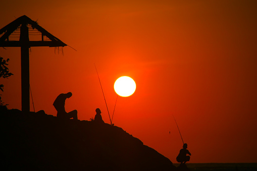Fishermen's silhouettes catch fish with a beautiful red sunset view on the coast of Lampuuk Aceh Besar Aceh, Indonesia, on February 15, 2019