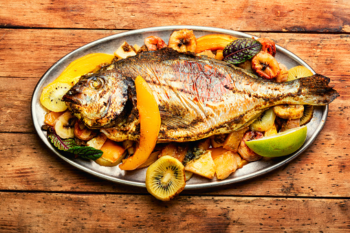 Appetizing river carp baked with fruits. Grilled fish