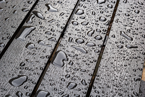 wet wooden planks of bench, background of wood texture with water drops from the rain, autumn mood.