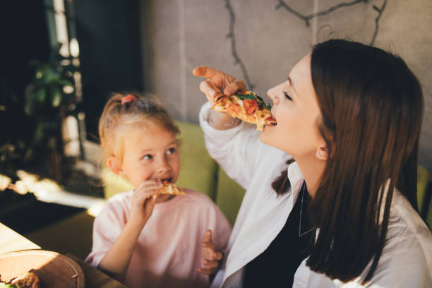 istock Mother and daughter eat pizza in a cafe. 1459913829