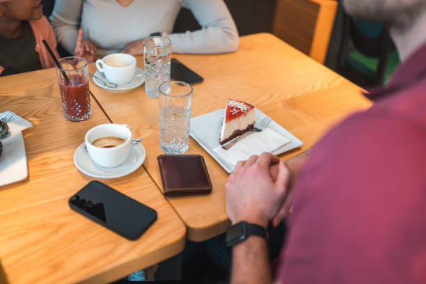 famiglia diversificata che gode di bevande calde e mangia dolci in un piccolo caffè - 13590 foto e immagini stock