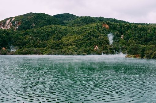 A steam coming out of a beautiful body of water surrounded by green mountains