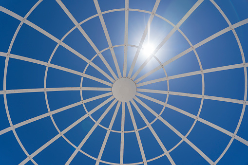 View on metal gazebo above blue sky on sunny summer day, close up