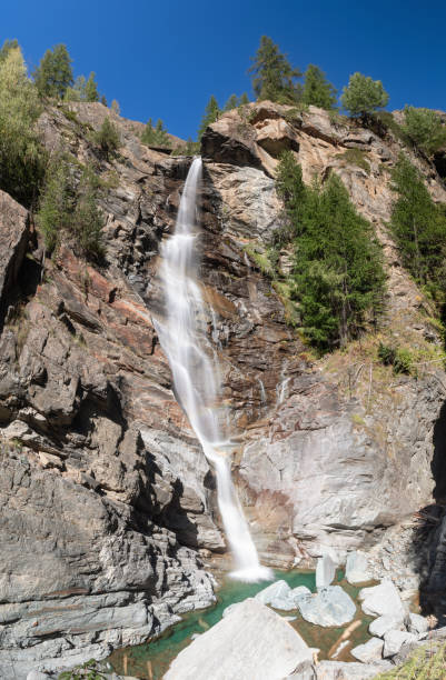 istock Foaming streams of mountain alpine Lillaz waterfall (Cascate di Lillaz) rush down granite rapids to small pond in Gran Paradiso National Park. Vertical shot, Aosta valley, Italy 1459915541