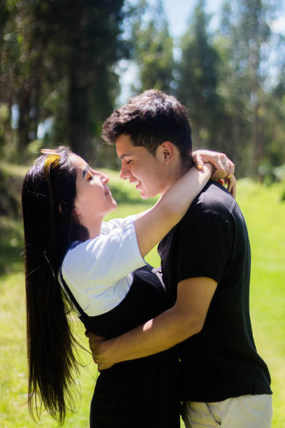 A vertical shot of a young couple hugging on a sunny day