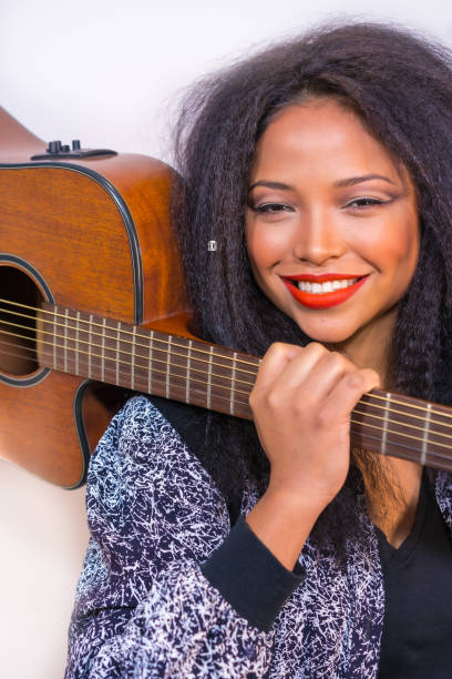 istock Young smiling Hispanic female posing at the camera holding a guitar on her shoulder 1459916786