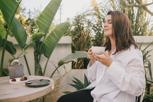 Young woman enjoying a cup of cappuccino at the garden.