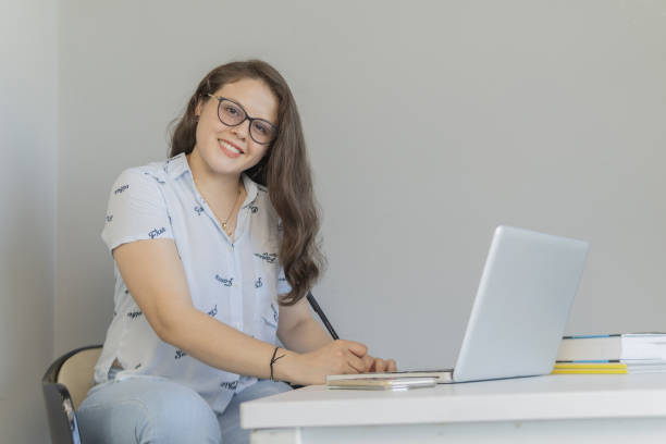 istock Young caucasian female smiling at the camera while working with a laptop 1459916992