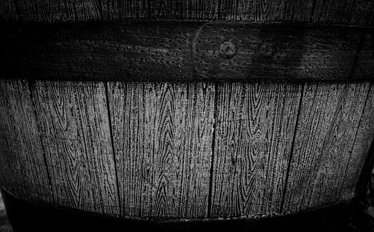 A grayscale closeup of a wooden barrel