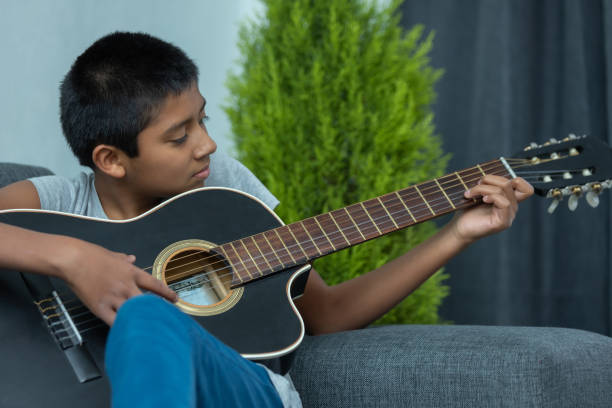 istock Mexican boy playing the guitar at home - homeschooling concept 1459918843