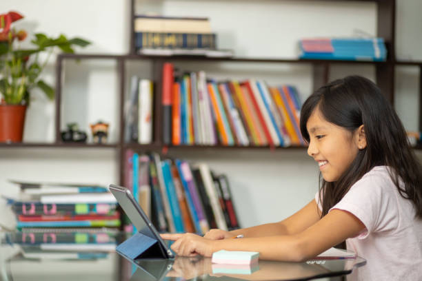 istock Hispanic schoolgirl doing a homework using a notebook and tablet at home - online education 1459918855