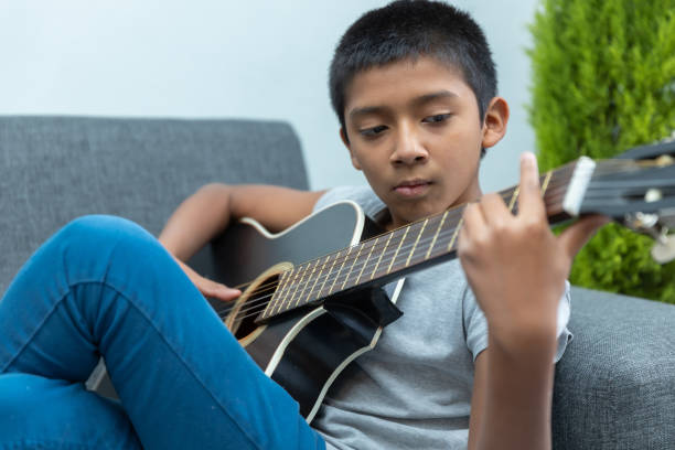 istock Boy sitting on the couch and playing guitar 1459919239