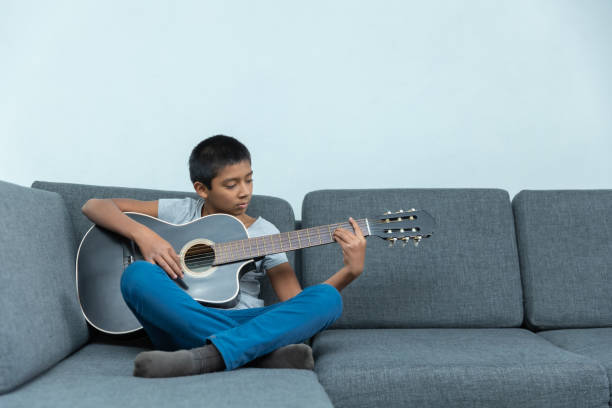 istock Little boy sitting on the couch and playing guitar 1459919249