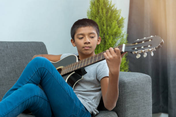 istock Boy sitting on the couch and playing guitar 1459919303