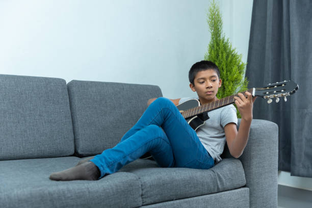 Little boy sitting on the couch and playing guitar