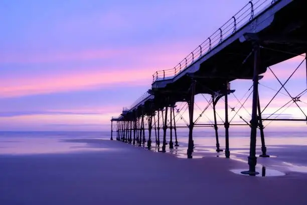 A scenic sunset cloudscape reflecting on the beach behind the Saltburn Pier