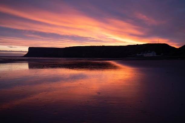 istock Scenic sunset clouds reflecting in the waves washing the sandy coastline 1459921279