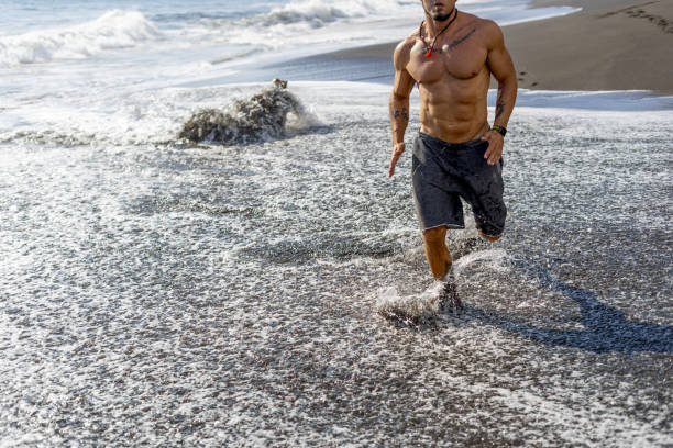 istock Young man doing a running workout at the beach 1459921429